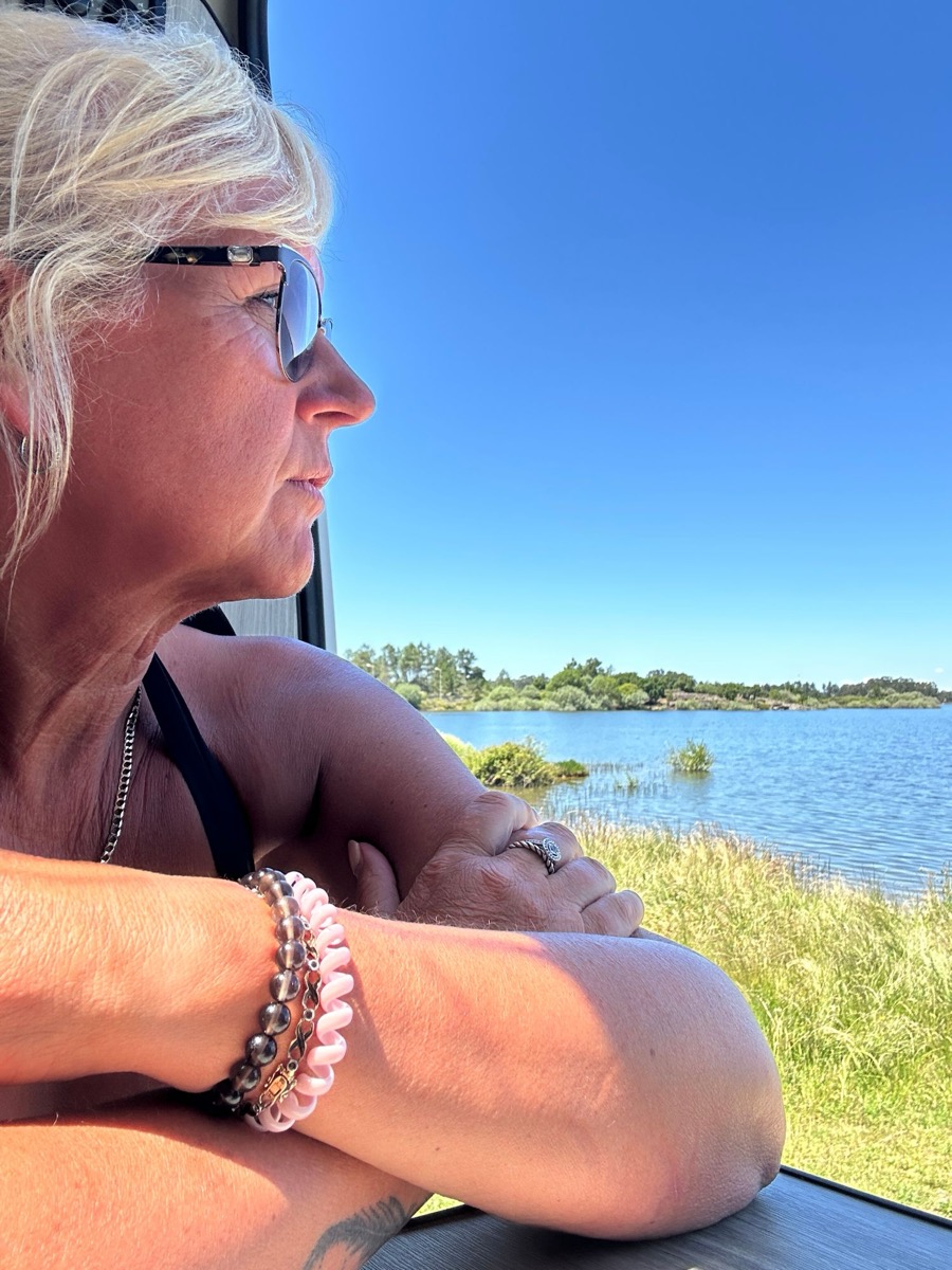 Yvonne looking out over a lake from her campervan window